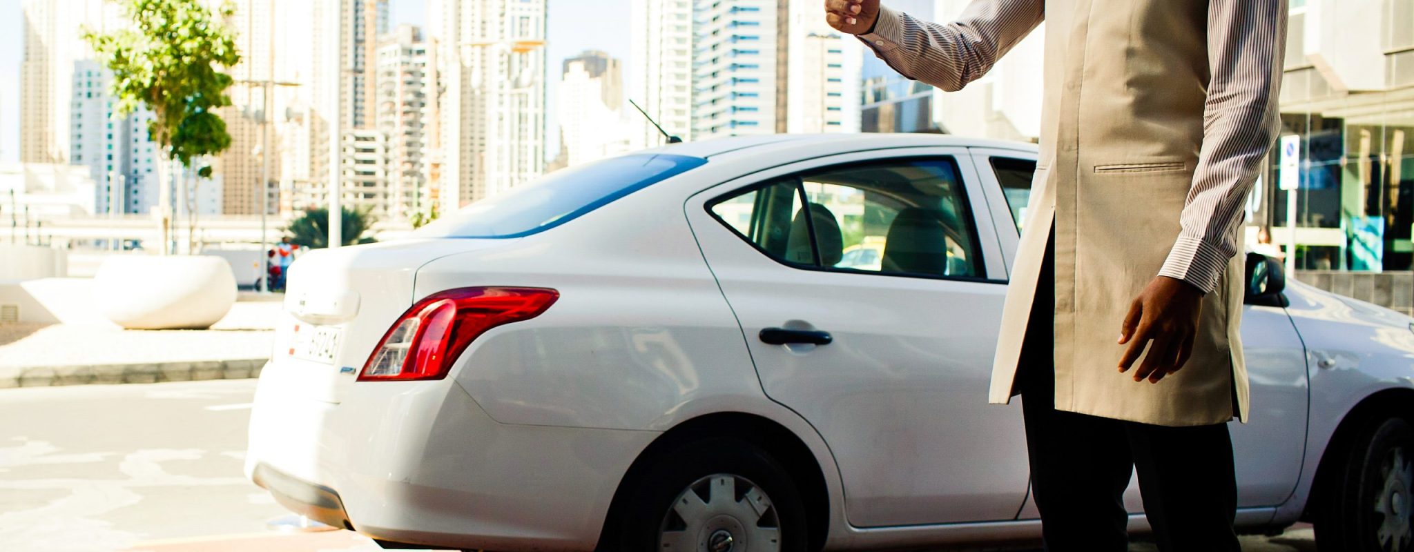Parking valet in beoge suit stands before white Peugeout